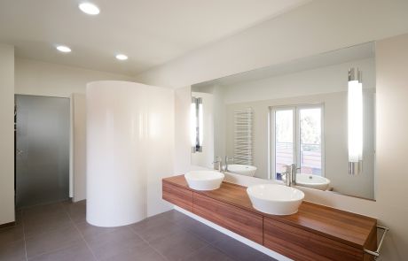 modernes Bad mit Holzwaschtisch und weißem Waschbecken und runder Dusche
