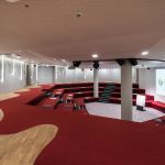 Konferenzraum mit rotem Teppichboden und treppenartigen Sitzplätzen