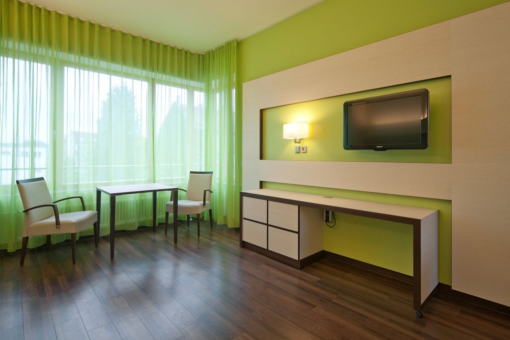 Komfortzimmer mit grünen Vorhängen und grüner Wandfarbe im Krankenhaus