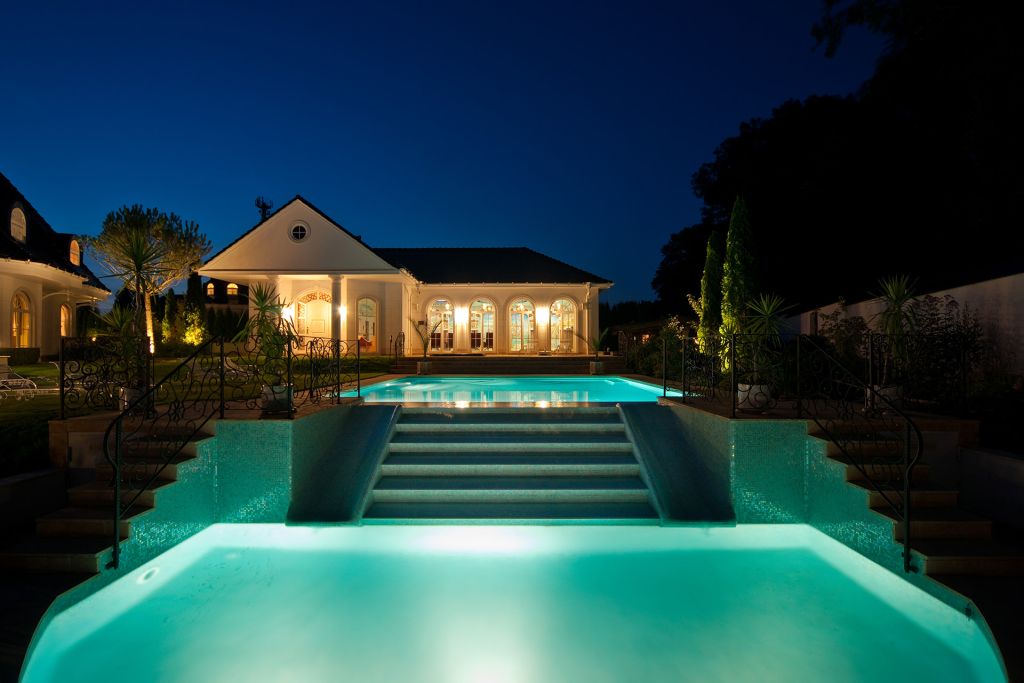 beleuchteter Pool und Poolhaus bei Nacht