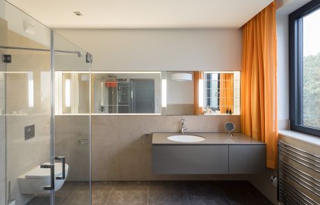 Modernes Badezimmer mit grauen Badmöbeln und Glasdusche in Penthousewohnung