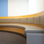 Runde Sitzbank im Klinik-Wartebereich, mit grauen Polstern und geschwungener Form