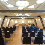Konferenzraum mit Holztischen und dunkelblauen Stühlen