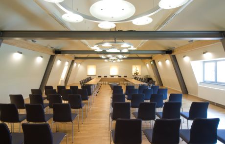 Konferenzraum mit Holztischen und dunkelblauen Stühlen