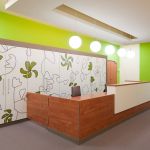 Empfangstresen aus Holz und grüne Wandgestaltung