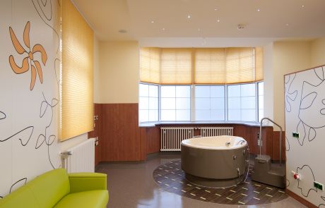Modern gestalteter Kreißsaal mit Gebärwanne und farbenfroher Wanddekoration