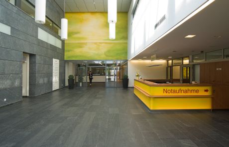 große Eingangshalle mit gelben Tresen und grüner Wandgestaltung