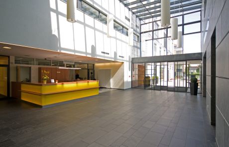 Helle Empfangshalle im Städtischen Klinikum Dresden mit gelbem Empfangstresen und Glasfassade