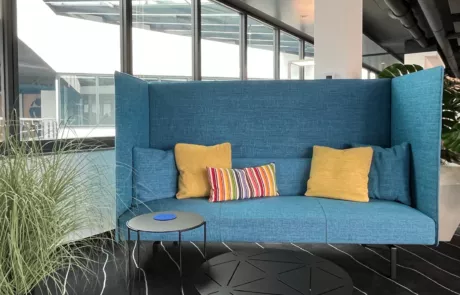 großes blaues Sofa mit gelben Kissen im Großraumbüro