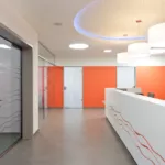 Empfangsbereich mit weißem Tresen und runden Deckenleuchten