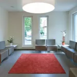Wartezimmer mit grauen Stühlen und rotem Teppich