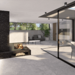 Offener Wohnraum mit Kamin, moderner Küche, Essbereich und großflächiger Verglasung zur Terrasse bei Tageslicht.